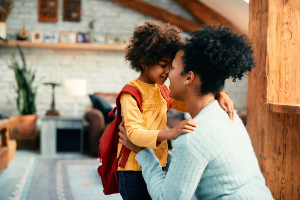 small black schoolgirl greeting with her mother at home on her first day of school. - parents imagens e fotografias de stock