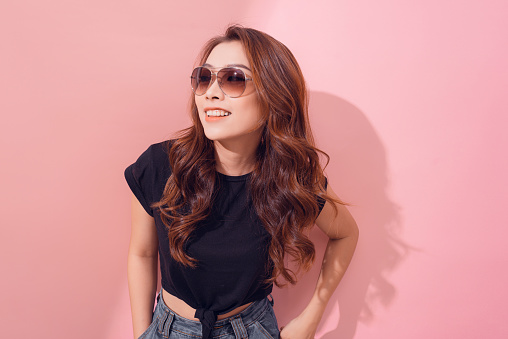Portrait of smiling beautiful girl in sunglasses against of pink background