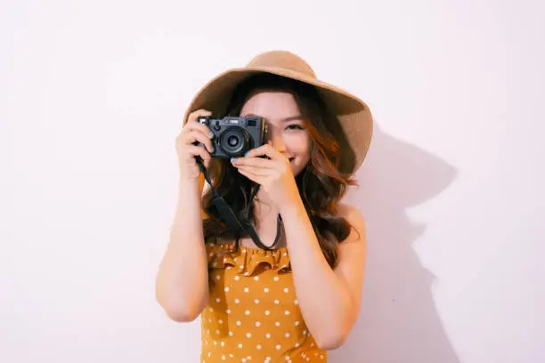 Happy young woman holding retro photo camera, isolated on pastel background