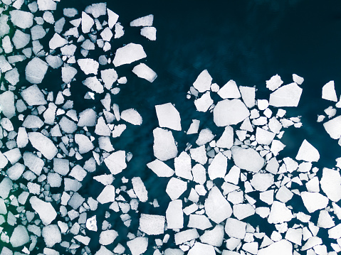 Ice floes on the water surface of the lake. Aerial top down view. Baikal lake, Siberia, Russia. Abstract nature background
