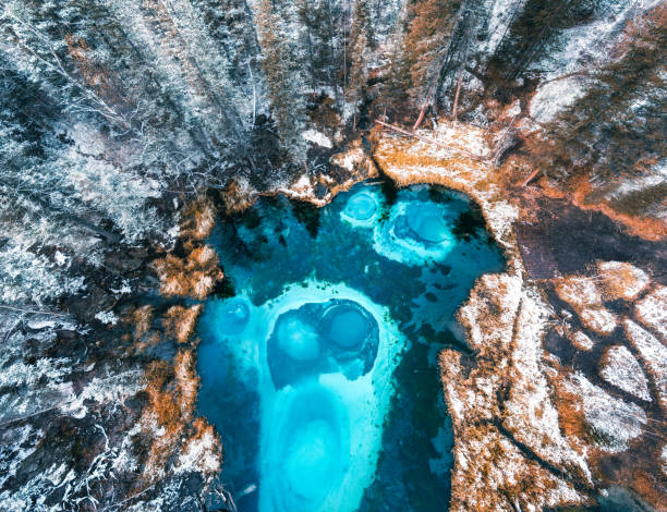 istock Blue geyser lake in autumn forest after snowfall. 1357075742