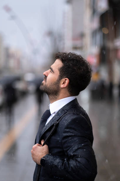 Portrait of young blond short hair latin man standing outdoors looking at camera posing, with commercial buildings in background with copy space.