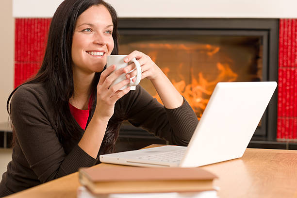 Home living woman with laptop by fireplace stock photo