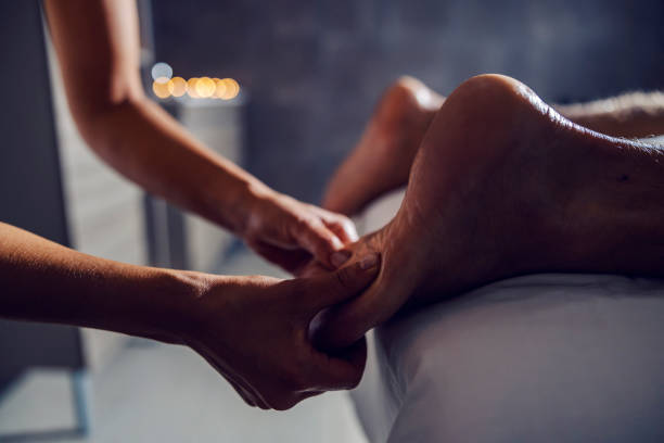 nahaufnahme einer erfahrenen masseurin, die die füße des mannes massiert. entspannung und gesundes leben. fußmassage im spa. - aromatherapy oil massage oil alternative therapy massaging stock-fotos und bilder