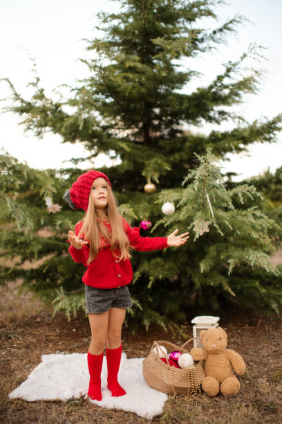 istock Kid girl decorating Christmas tree outdoors 1357084994