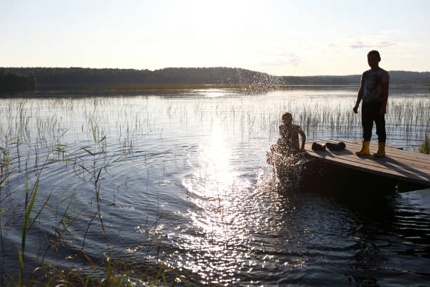 istock Boys playing on wooden bridge by lake 1357094100