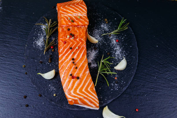istock Raw salmon fillet with spices on black slate. Top view 1357094131