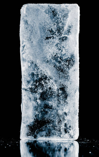 istock Textured frosty ice block on reflective mirroring surface on black background. 1357095168