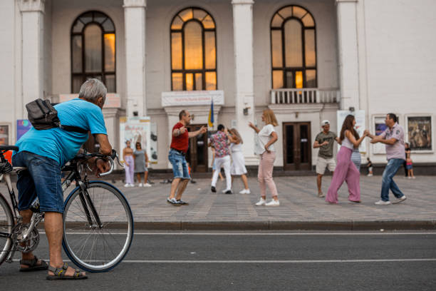 Man on bike looking on people dancing in the center of a city Ukraine, Mariupol - August 9, 2021: Man on bike looking on people dancing in the center of a city mariupol stock pictures, royalty-free photos & images