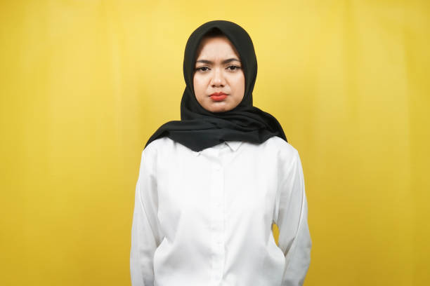 Beautiful asian young muslim woman pouting looking at camera isolated on yellow background stock photo