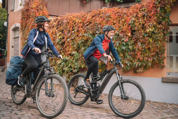 Couple ride e-mountain bikes through city They ride through the cobblestone streets of Lugano electric bicycle stock pictures, royalty-free photos & images