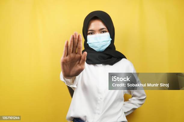 Muslim Woman Wearing Medical Mask With Stop Sign Hand Rejection Sign Hand Do Not Keep Distance Sign Hand Do Not Approach Hand Sign Isolated On Yellow Background Stock Photo - Download Image Now