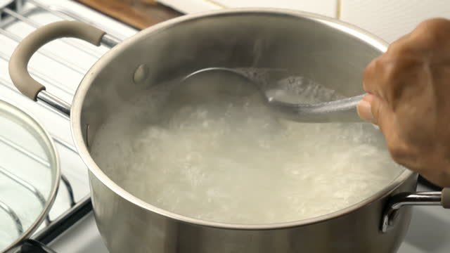 Closeup cooking and stirring hot boiled rice.