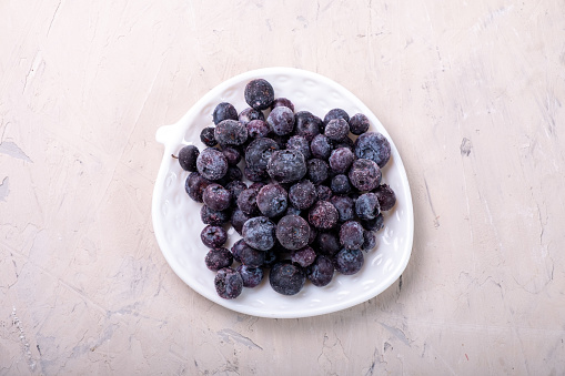 Frozen blueberries on a white plate, top view.