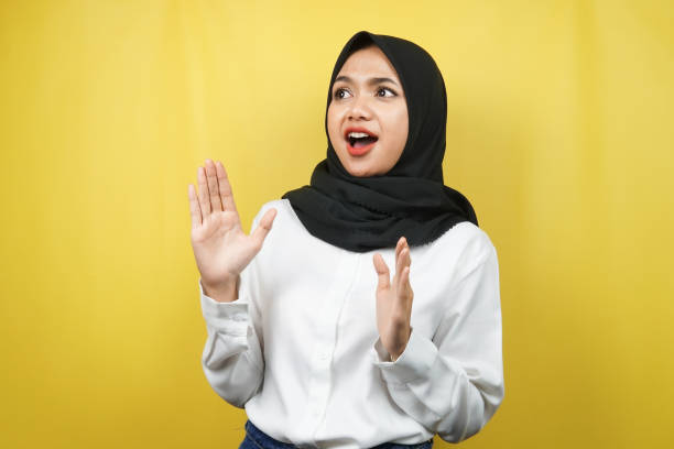 istock Beautiful young asian muslim woman shocked, surprised, wow expression, looking at empty space, isolated on yellow background 1357101784