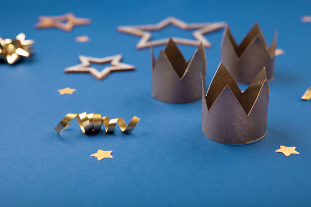 Three gold crowns for Traditional Three King's Day of January 6, blue background. Traditional Three King's Day of January 6. Three gold crowns on blue background with winter decorations. Happy Epiphany day. Selective focus, copy space. religious christmas greetings stock pictures, royalty-free photos & images