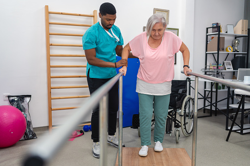 senior adult patient doing physiotherapy at a clinic with help of a therapist