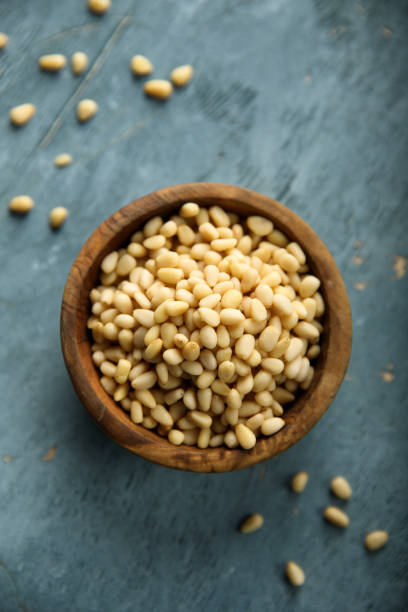 Pine nuts Organic pine nuts in a wooden bowl pinion stock pictures, royalty-free photos & images