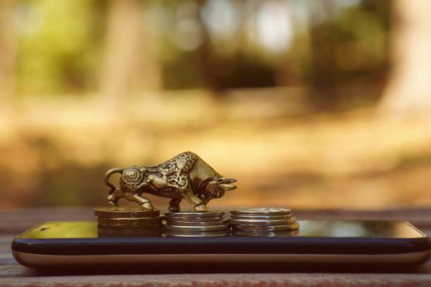 istock Bull figurine with coins on a mobile phone. 1357110680