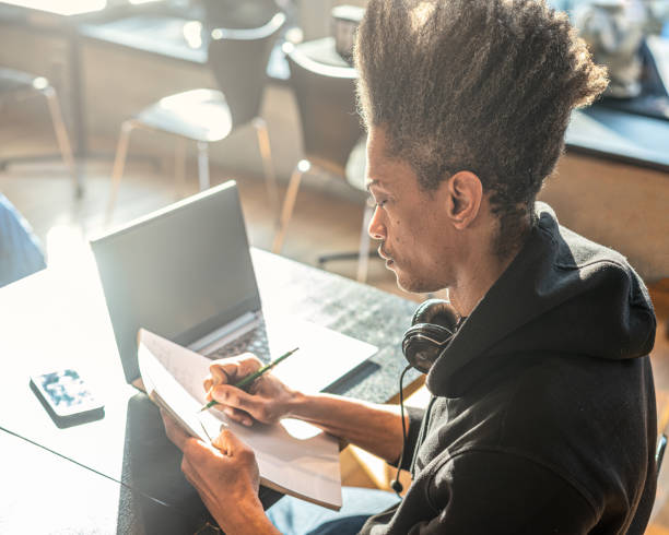 junger afroamerikanischer mann, der mit laptop lernt, notizen auf notebook macht, junger lateinamerikaner bereitet sich mit modernen technologischen verbindungen auf eine universitätsprüfung vor, lifestyle-konzept copy space - library student latin american and hispanic ethnicity university stock-fotos und bilder