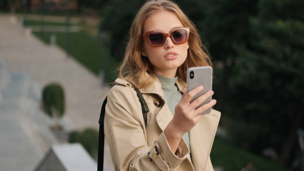 istock Beautiful blond student girl in sunglasses looking sensual taking selfie on smartphone while resting in city park. Stylish blogger girl 1357112883