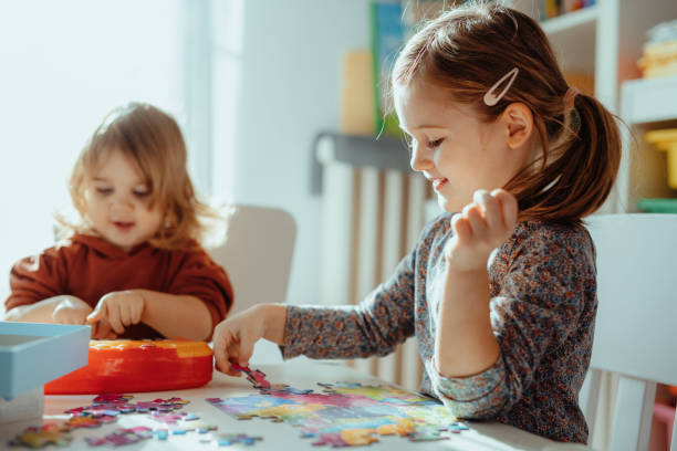 istock Sisters playing in the room at home with jigsaw puzzle 1357115087