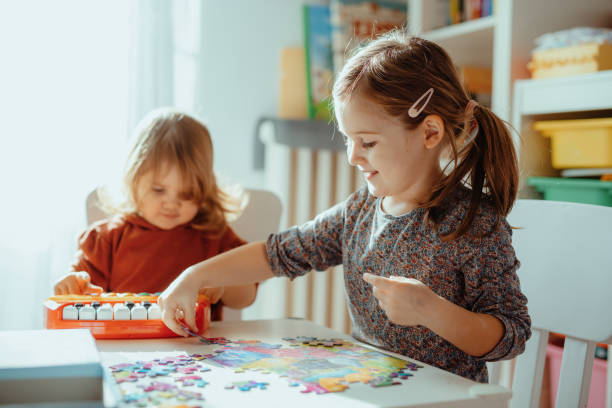 istock Sisters playing in the room at home with jigsaw puzzle 1357115090