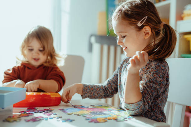 istock Sisters playing in the room at home with jigsaw puzzle 1357115096