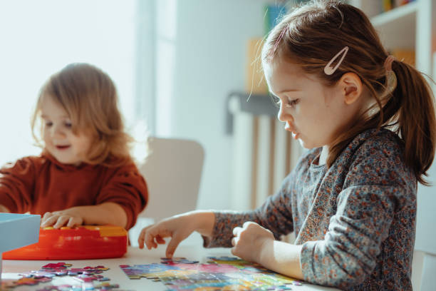 istock Sisters playing in the room at home with jigsaw puzzle 1357115104