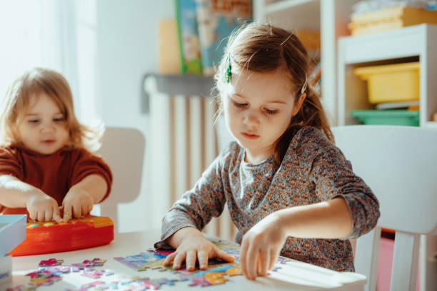 istock Sisters playing in the room at home with jigsaw puzzle 1357115111