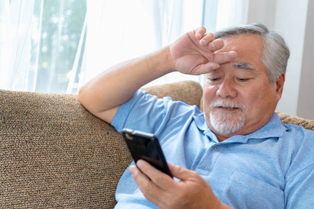 istock Mature man trying to use mobile phone. 1357115309
