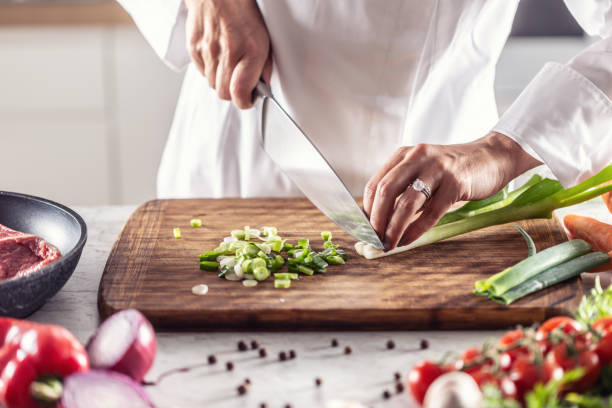 istock Chef finely chops spring onion on a wooden cutting board. 1357115323
