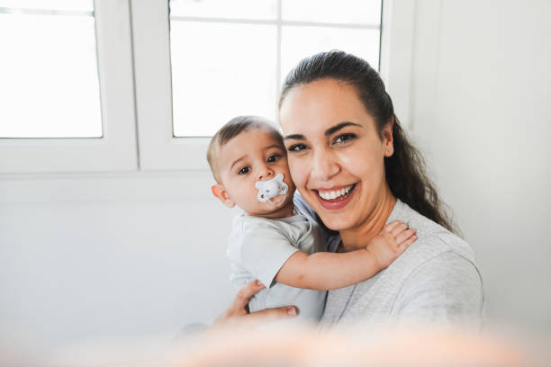 Young mother having fun taking selfie with her baby at home - Focus on mother face stock photo