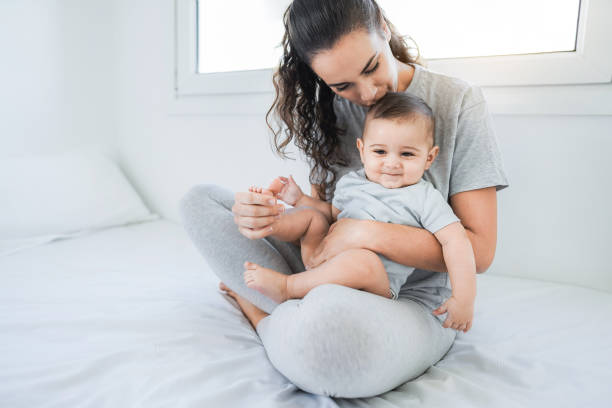 istock Young mother having fun with her baby on bet at home - Focus on kid face 1357123713