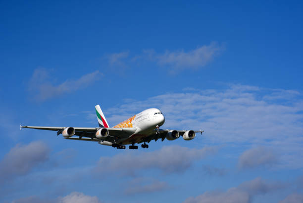 białe, czerwone, zielone i czarne samoloty zbliżające się do pasa startowego. - emirates airline zdjęcia i obrazy z banku zdjęć
