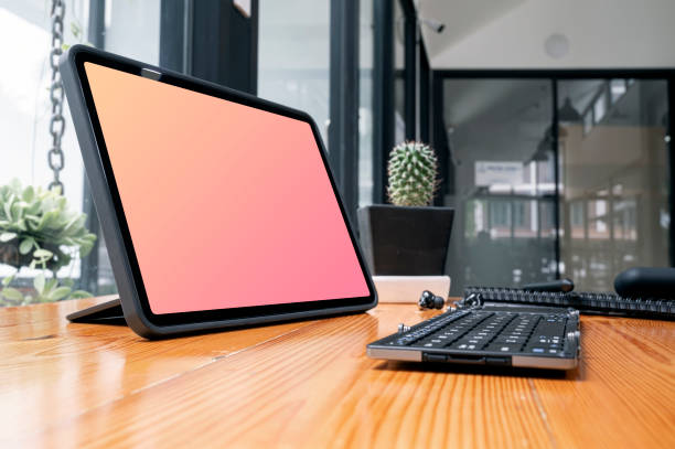 Closeup view of blank screen portable tablet with keyboard on wooden table.