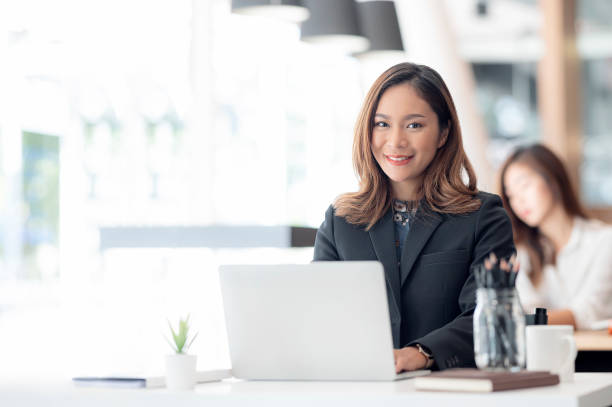 istock Beautiful asian businesswoman smiling and looking at camera while working on laptop computer at her office desk. 1357126954