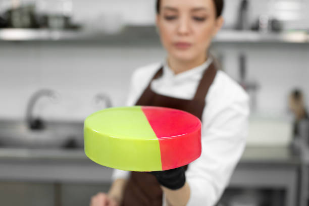 istock Young smiling brunette chef holds a mousse cake decorated with handmade chocolates. 1357127930