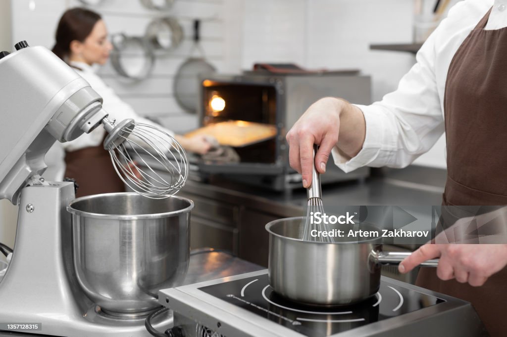 Male pastry chef cooks a berry kuli in a saucepan for filling a cake. 25-29 Years Stock Photo
