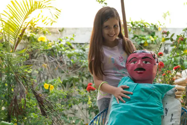 Photo of Young beautiful latin girl, making a kind of doll / monigote to burn at midnight of New Year's Eve in Ecuador.

Ecuador Popular Tradition.