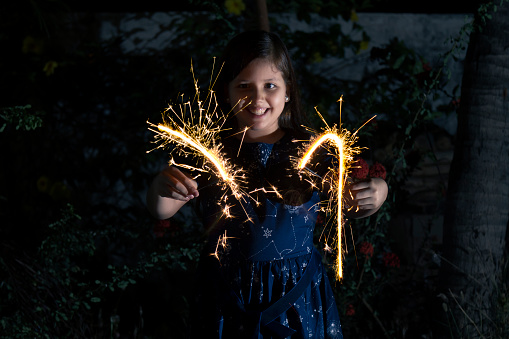 Young latin little girl outside celebrating New year's or Christmas Holidays playing with sparkles fireworks at Ecuador, Latin America.

Ecuador Popular Traditions at new year's eve.