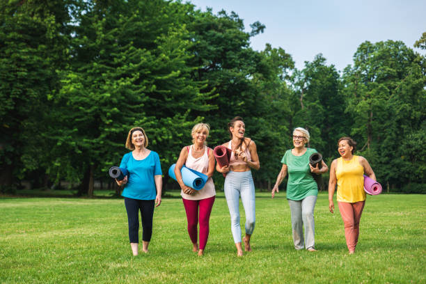 donne senior che si allenano con l'allenatore di fitness al parco - yoga meeting foto e immagini stock