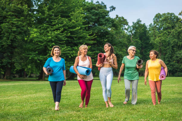 seniorinnen trainieren mit fitnesstrainer im park - yoga exercising outdoors group of people stock-fotos und bilder