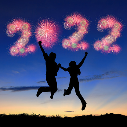 silhouette of young couple jumping with 2022 fireworks in the air