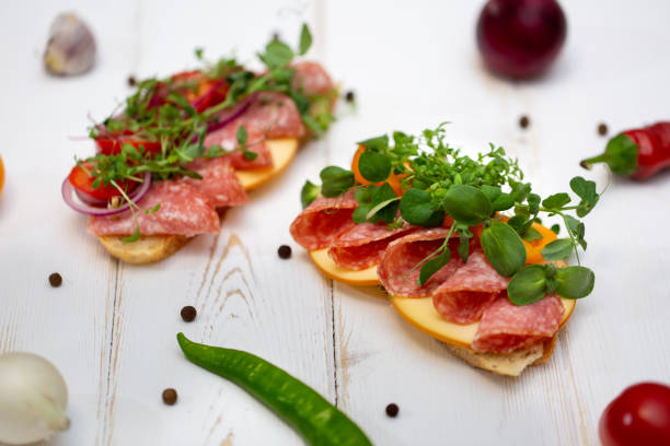istock Sandwiches with sausage, cheese and micro-greens on a white background 1357137475