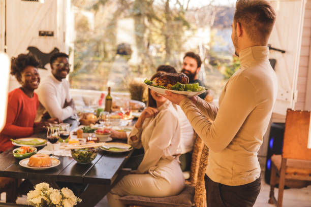 istock Young man serving roasted chicken for lunch with friends 1357144120