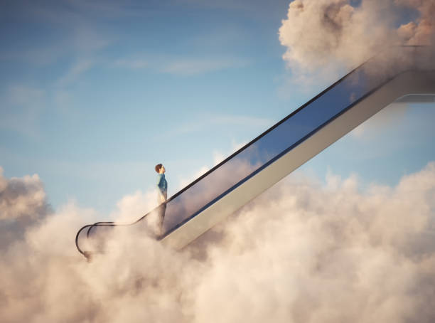 istock Man on escalator above clouds. Aspirations and promotion concept. 1357145603