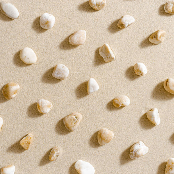 Pattern with close up pebble sea stones on sand texture. Layout from natural stone neutral natural tones. Minimal style sandy background