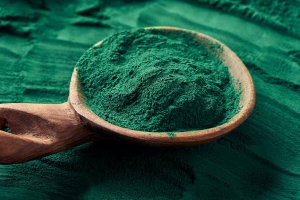 Green spirulina powder on a wooden spoon Green spirulina powder on a wooden spoon - healthy nutritional supplement chlorella stock pictures, royalty-free photos & images