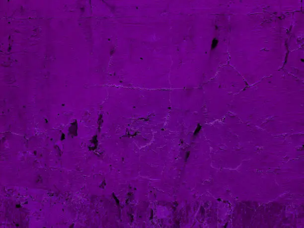 Photo of surface of purple old weathered plaster concrete wall background. abandoned and distressed violet stucco wall texture background.  wall fragment with scratches and cracks.